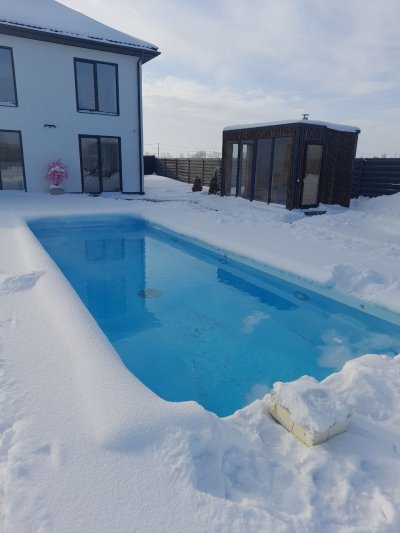 Открытый прямоугольный бассейн зимой на заднем дворе частного дома со снегом